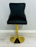 A black and gold bar stool with a tufted backrest and a gold lion knocker.