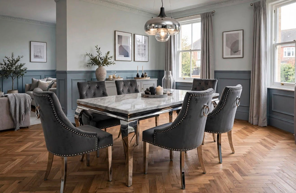 Louis light grey marble dining table with polished chrome base and dark grey velvet Majestic chairs in a blue-grey panelled dining room with herringbone flooring