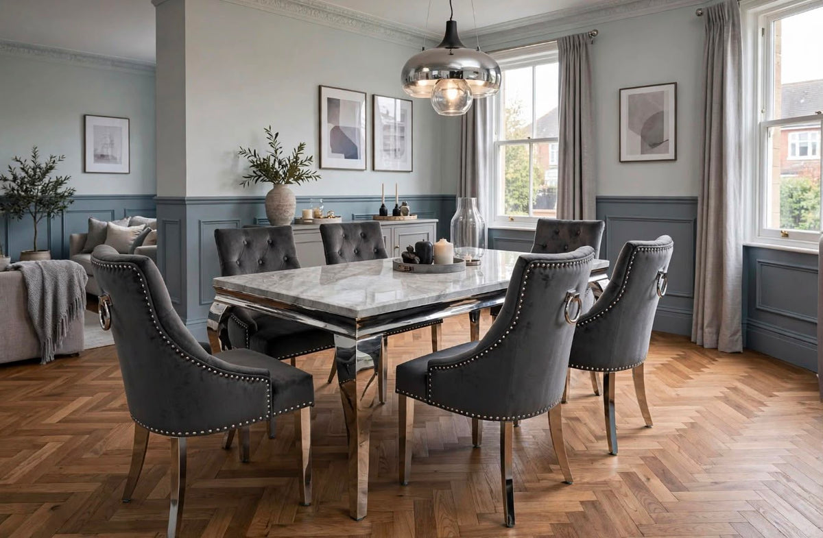 Louis light grey marble dining table with polished chrome base and dark grey velvet Majestic chairs in a blue-grey panelled dining room with herringbone flooring
