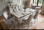 Louis light grey marble dining table with eight silver velvet Jessica chairs with tufted backs on a patterned rug in a classic dining room